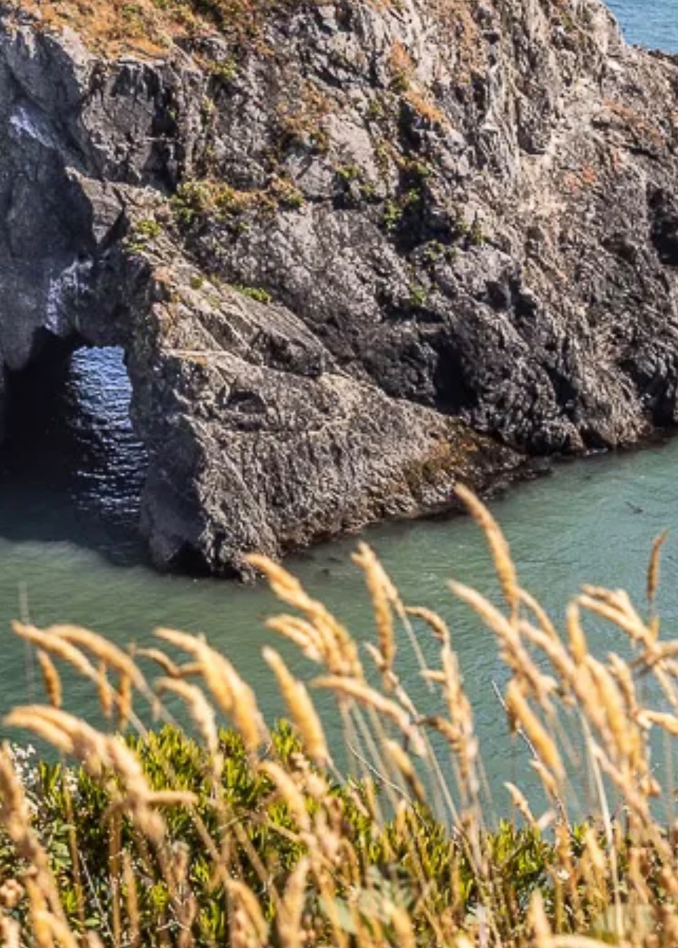 Clear turquoise water below rugged sea cliffs