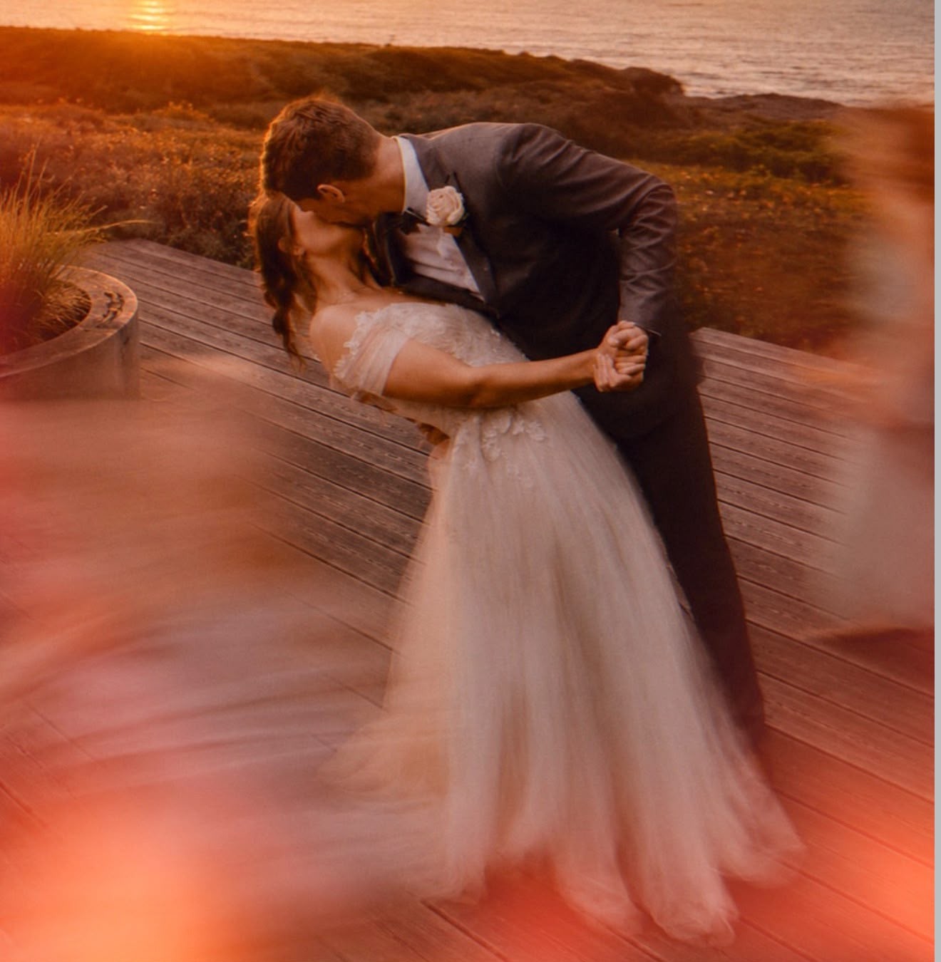 A newly married couple embracing at sunset on the oceanfront terrace
